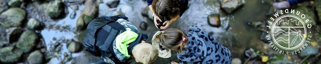 Three students doing water testing in a stream